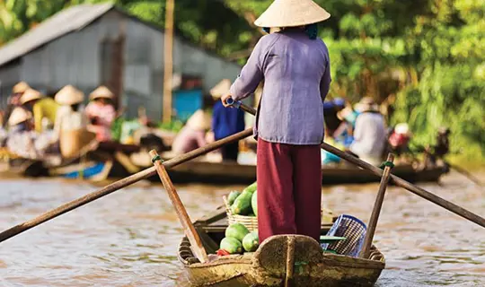 A woman stood in a rowing boat on a canal, Vietnam